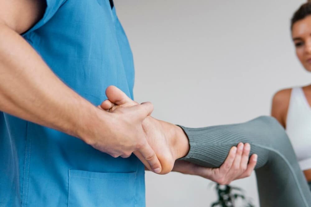 terapeuta osteopático masculino controla movimiento pierna paciente