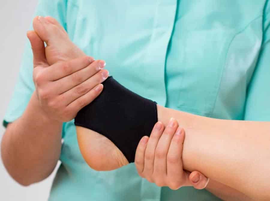 fisioterapeuta sujetando el tobillo de un paciente